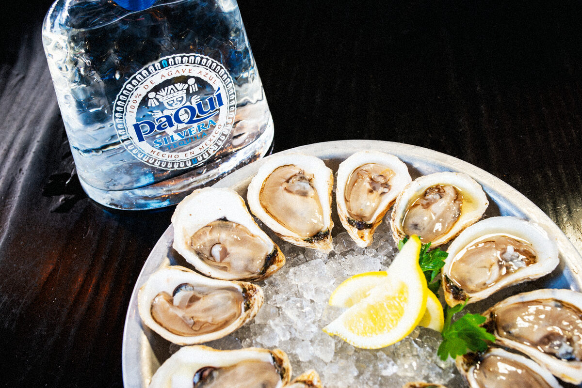 PaQui Tequila bottle paired with fresh oysters on ice platter